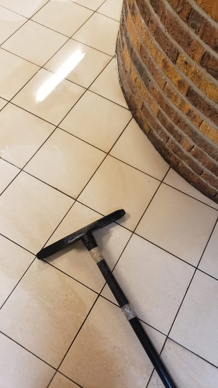 Rinçage à la raclette du sol carrelé après décapage