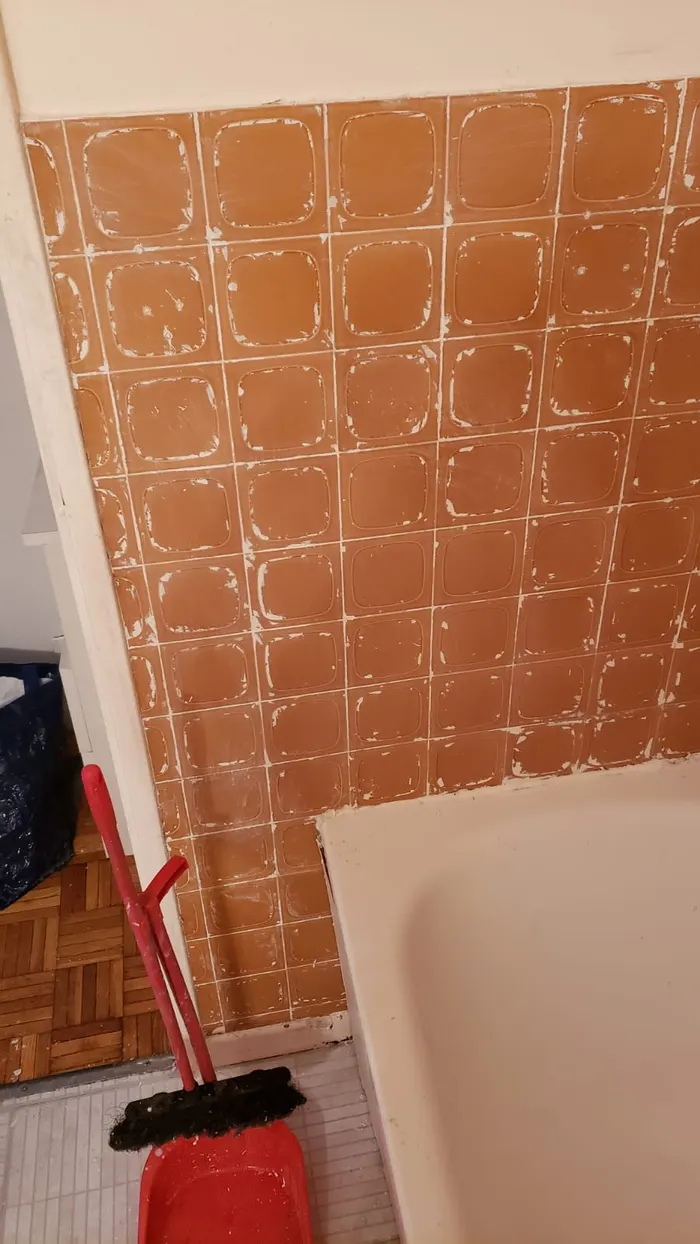 Mur du pied de baignoire décapé, déchets de peinture évacués.