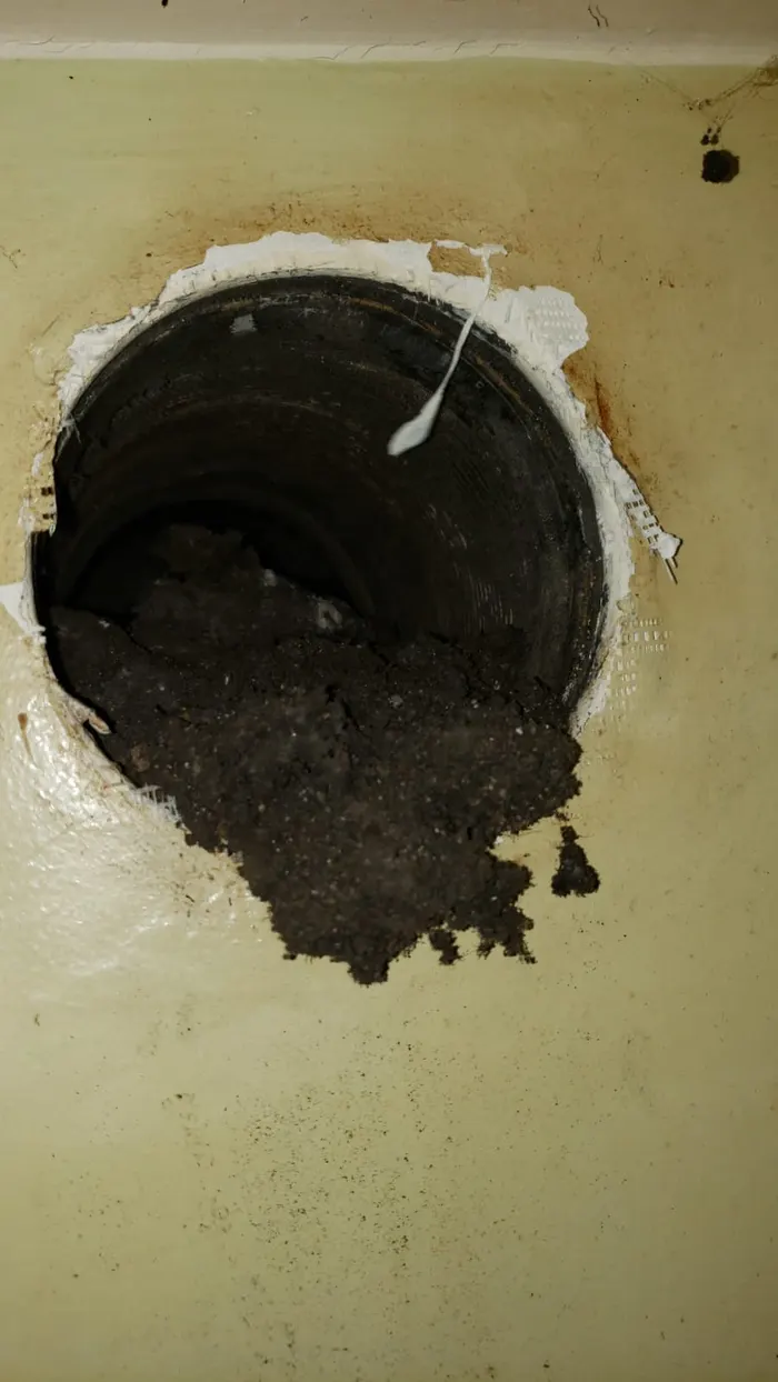 Conduit de ventilation encrassé dont les dépôts débordent et salissent le mur avant intervention.